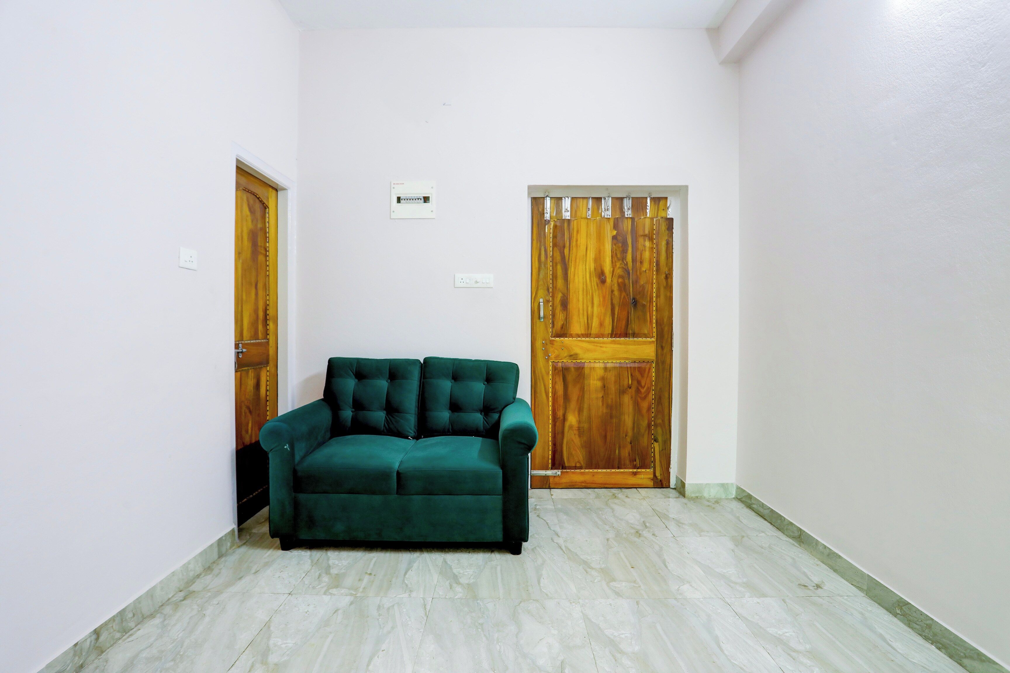A room with a green sofa, two wooden doors, and a white wall.