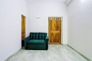 Una habitación con un sofá verde, dos puertas de madera y una pared blanca.