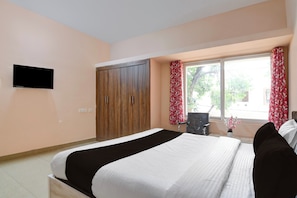 A bedroom with a bed, a wardrobe, a chair, a television, and a window with curtains. - Hotel O by OYO Happy Stay (Bhubaneswar)