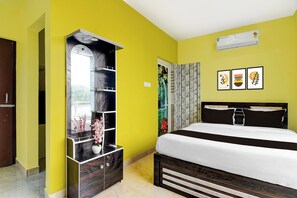 A bedroom with a bed, a wardrobe, a mirror, a window, and a wall-mounted air conditioner. - Hotel O Royal Avisi Residency (Bhubaneswar)