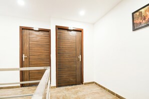 A hallway with two closed wooden doors, a white wall, and a tiled floor. - Hotel O Sayhallo Citadel (Bhubaneswar)