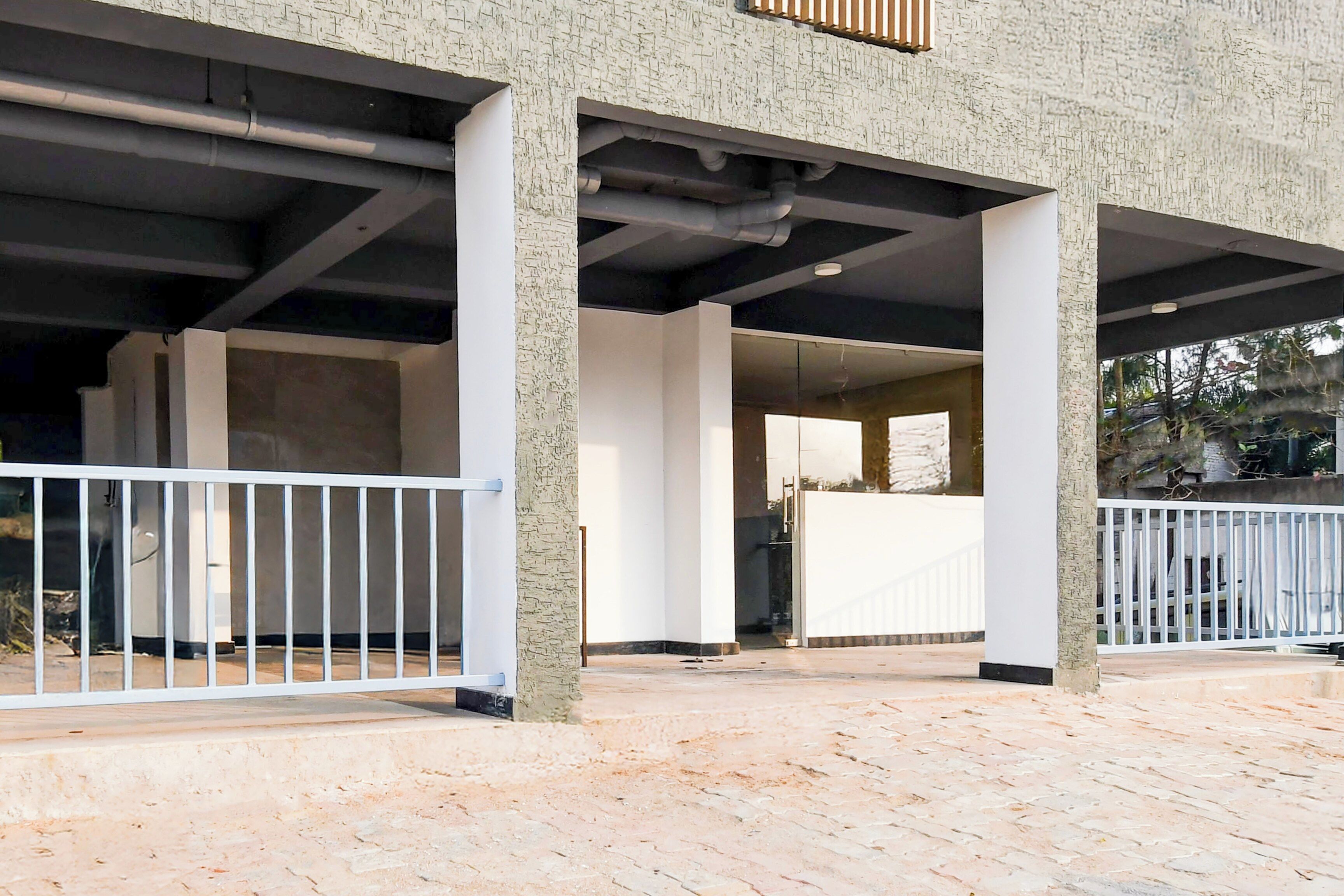 A building with a covered outdoor area, columns, and a white railing.