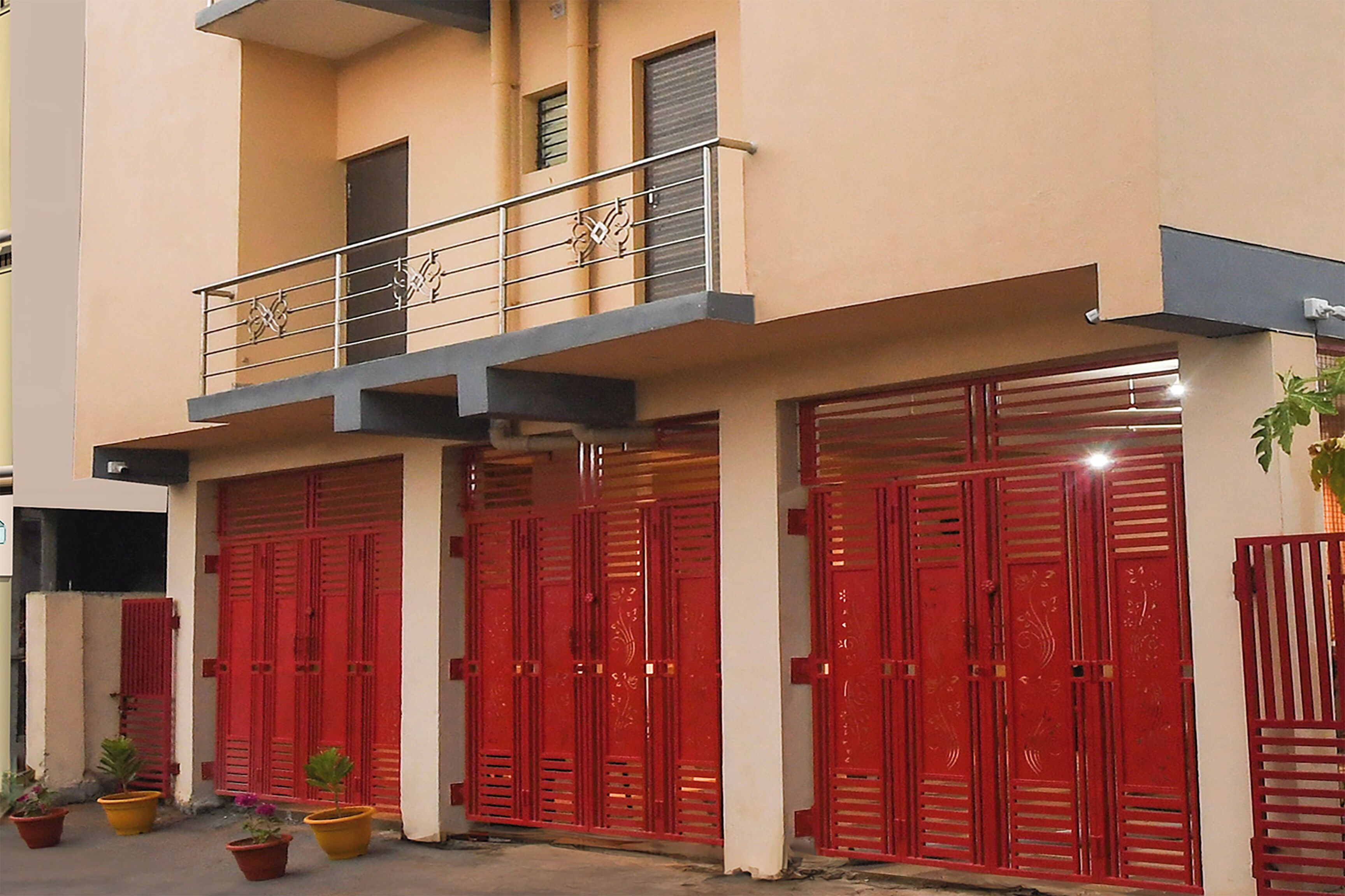 A two-story building with a balcony and large red doors.