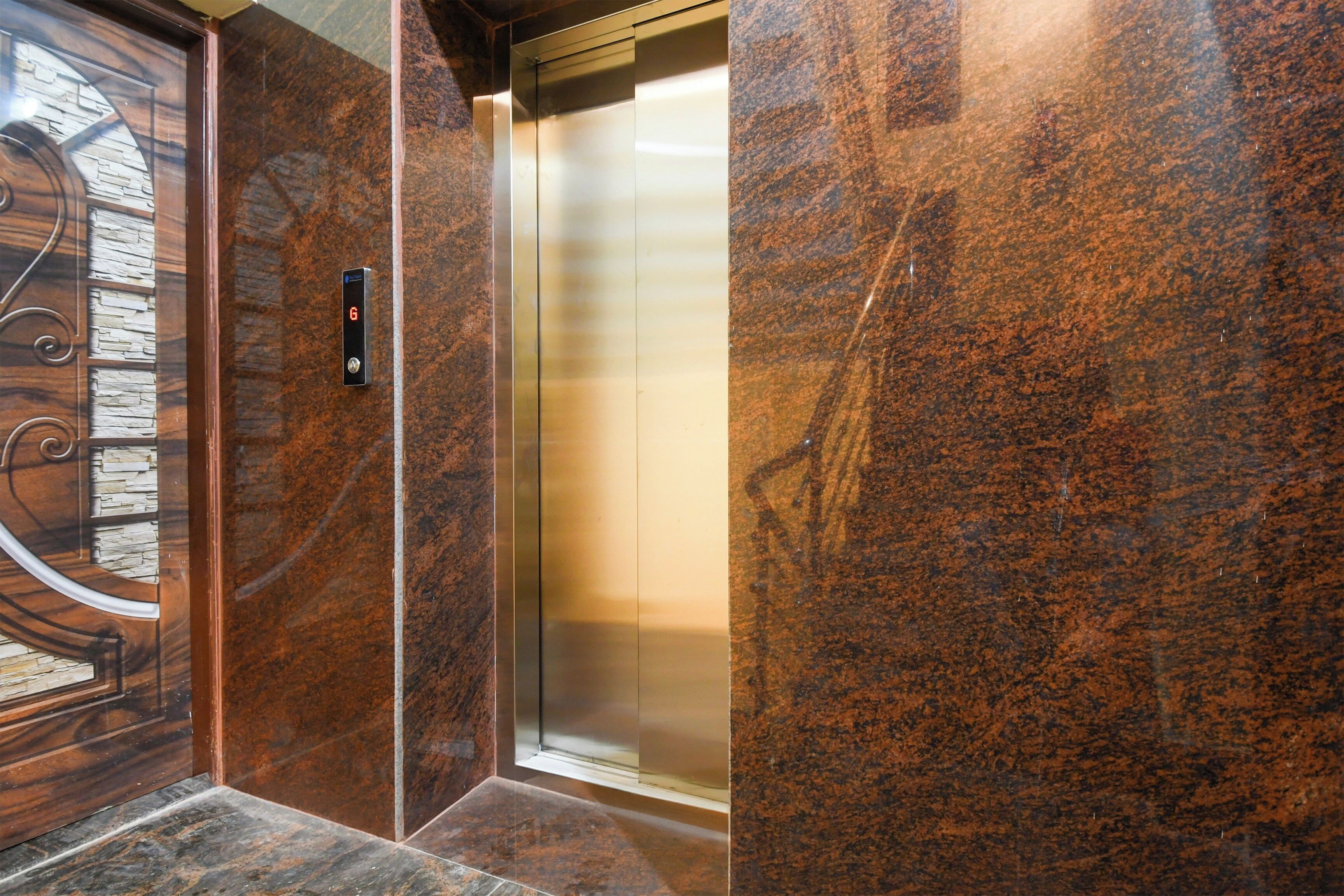 A modern elevator with a metallic interior and a stone wall with a textured pattern.