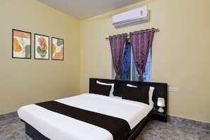 A hotel room with a bed, a nightstand, a lamp, an air conditioning unit, and two framed artworks on the wall. - Hotel O Airport Residency (Bhubaneswar)