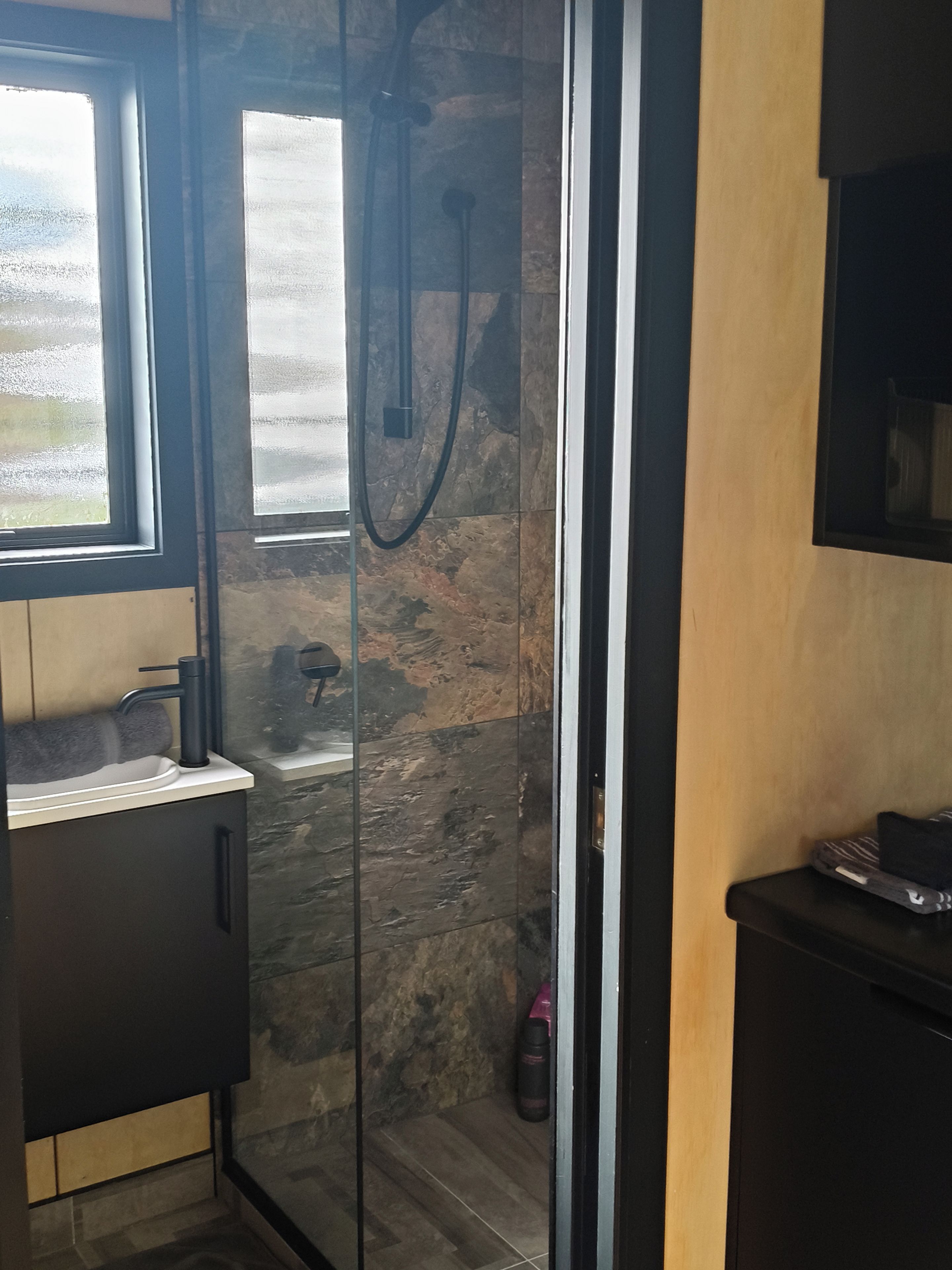 A bathroom with a glass shower enclosure, a sink, and a toilet.