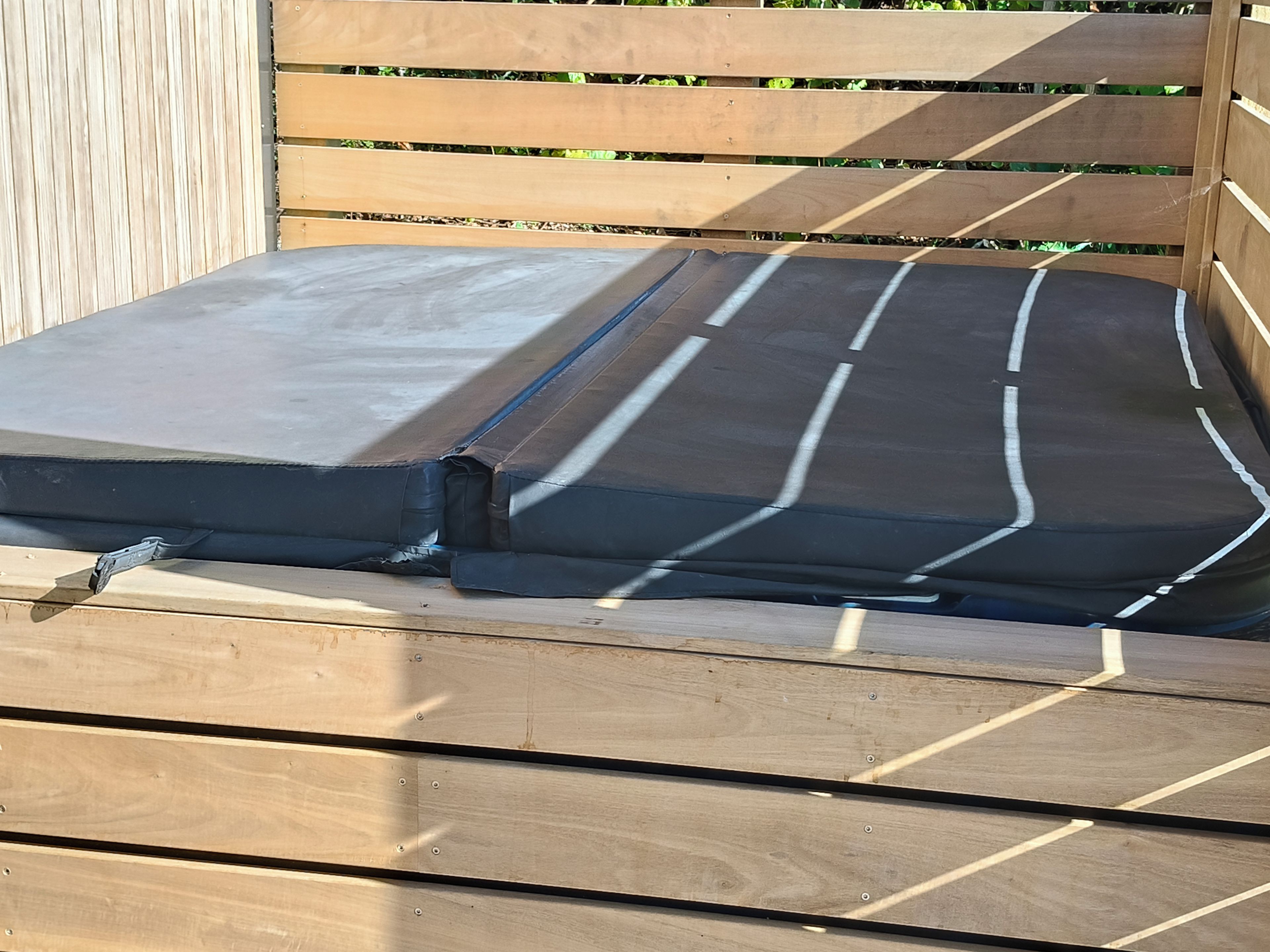 Een houten bank met een zwart beklede zitting.