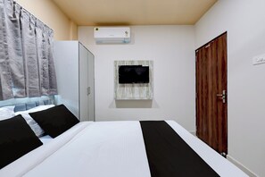 A hotel room with a bed, a wardrobe, a television mounted on the wall, and an air conditioning unit. - Hotel O Vishnupriya Holiday inn (Bhubaneswar)