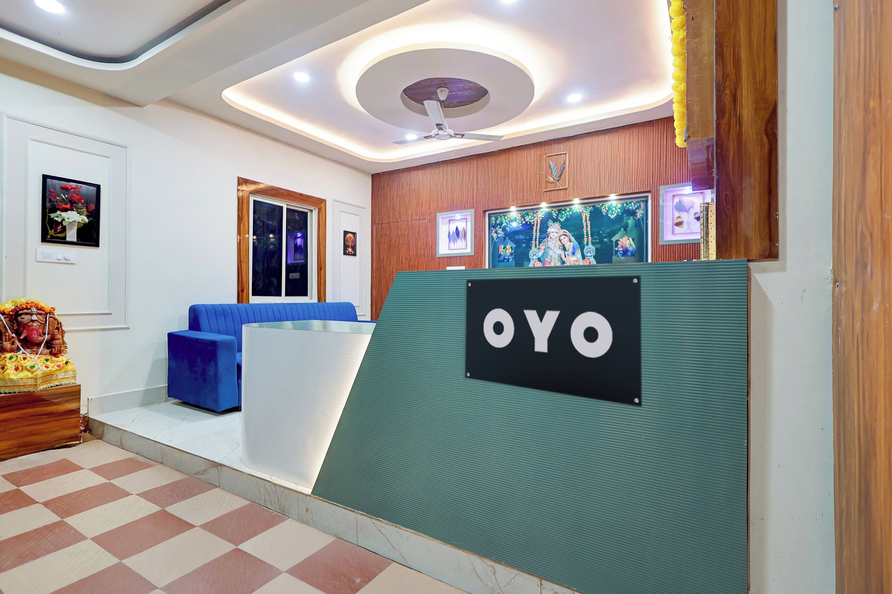 A reception area with a blue sofa, a wooden statue, and a sign that reads 'OYO'.