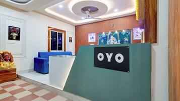 A reception area with a blue sofa, a wooden statue, and a sign that reads 'OYO'.