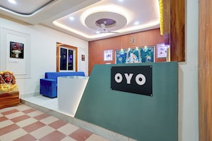 Zona de recepción con un sofá azul, una estatua de madera y un letrero que dice 'OYO'.