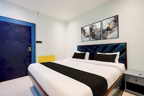A modern bedroom with a large bed, a nightstand, and a door. - Hotel O Sky Plex Guest House (Bhubaneswar)