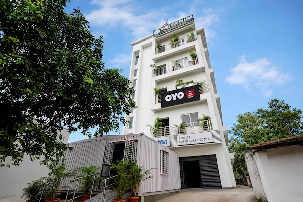 Un edificio de varios pisos con un cartel que dice 'Skyplek Residency & Cafe' y 'OYO Guest House' en la fachada.