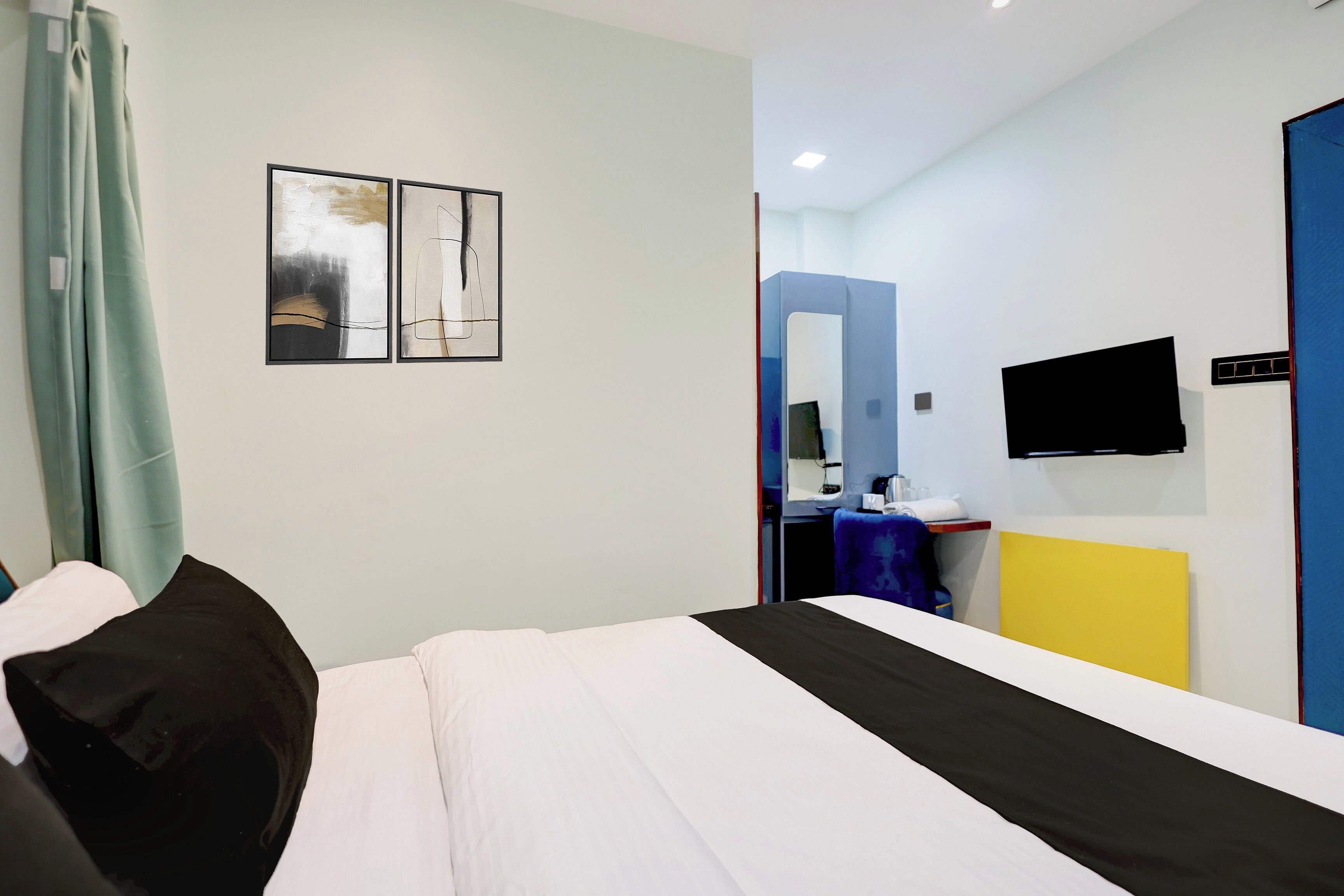 Una habitación de hotel con una cama, un televisor de pantalla plana montado en la pared y una ventana con cortinas.
