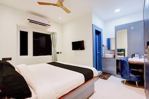 A hotel room with a bed, a desk, a chair, a mirror, a sink, and an air conditioning unit. - Hotel O Sky Plex Guest House (Bhubaneswar)