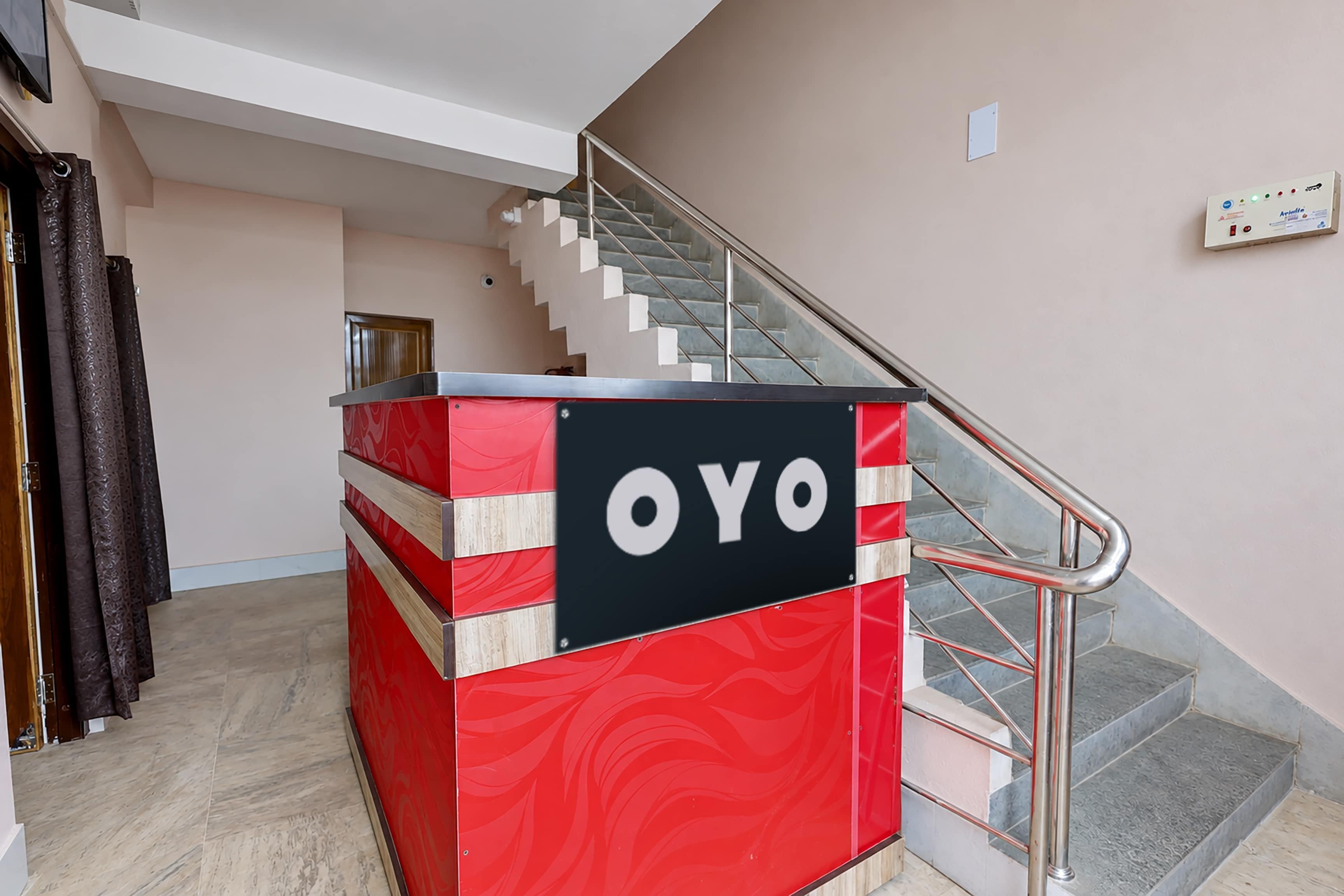 Un quiosco informativo rojo y negro con la palabra 'OYO', situado cerca de una escalera en un edificio.