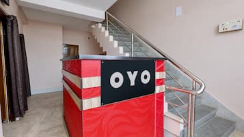 Un quiosco informativo rojo y negro con la palabra 'OYO', situado cerca de una escalera en un edificio.