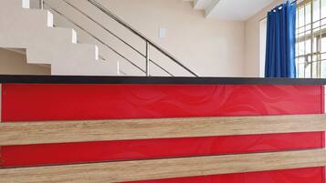 A staircase with a beige wall and a red panel at the bottom.