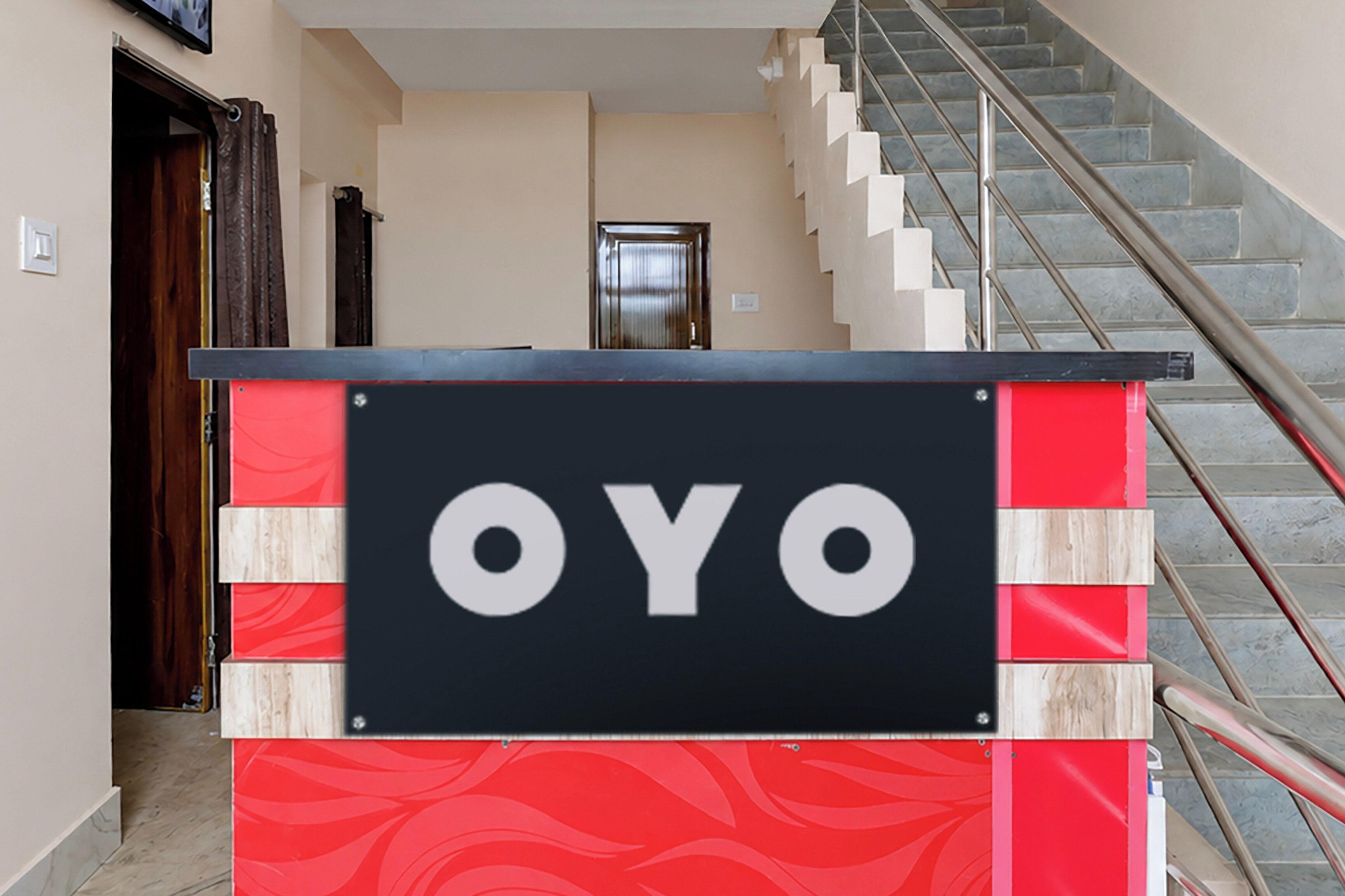A hotel entrance with a sign reading 'OYO' and a staircase leading to the upper floor.