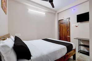 A hotel room with a bed, a desk, a television, and a door with a number. - Hotel O Temple City Guest House (Bhubaneswar)