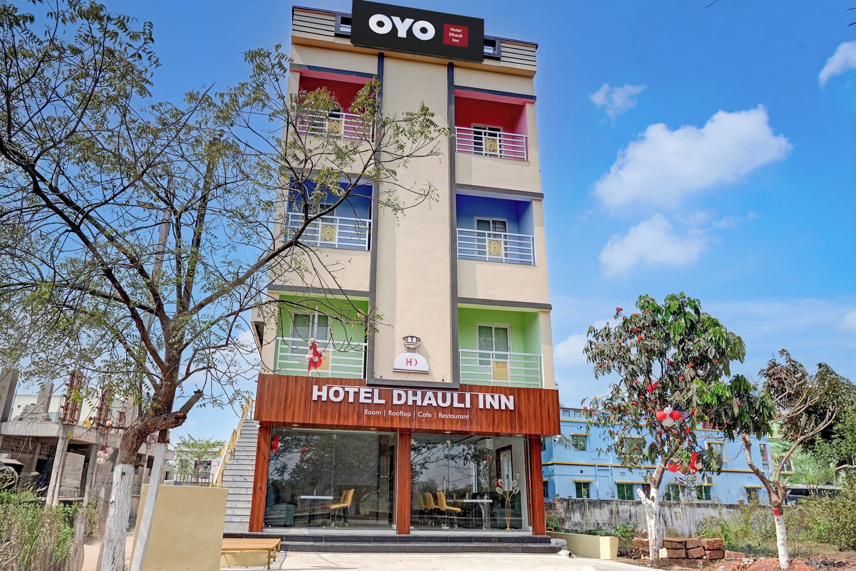 Un edificio de hotel de varios pisos con un cartel que dice 'HOTEL DHAULI INN' y un cartel con la palabra 'HOTEL' encima.