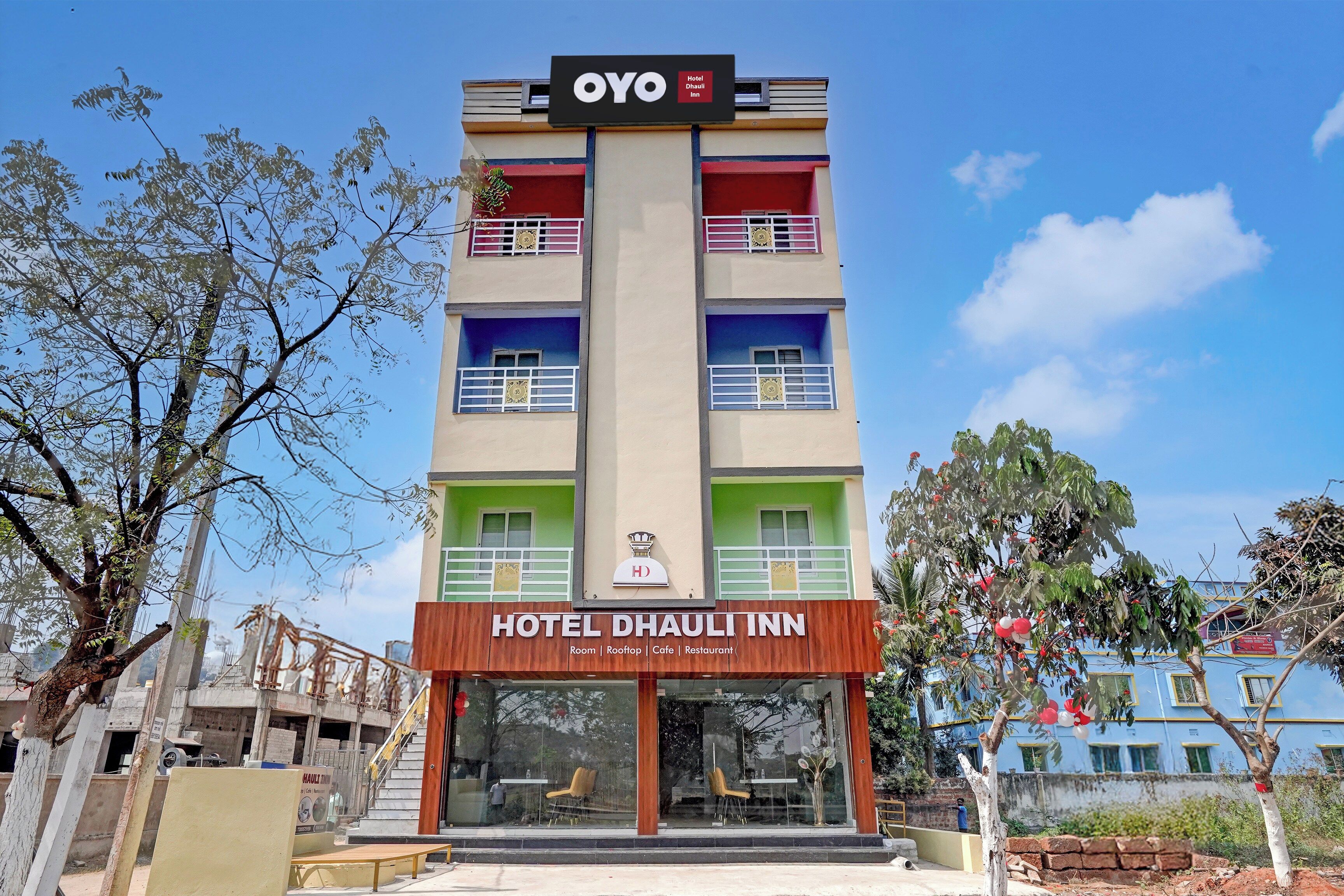 Un hotel de varios pisos con un letrero que indica que es el Hotel OYO Dhauli Inn.