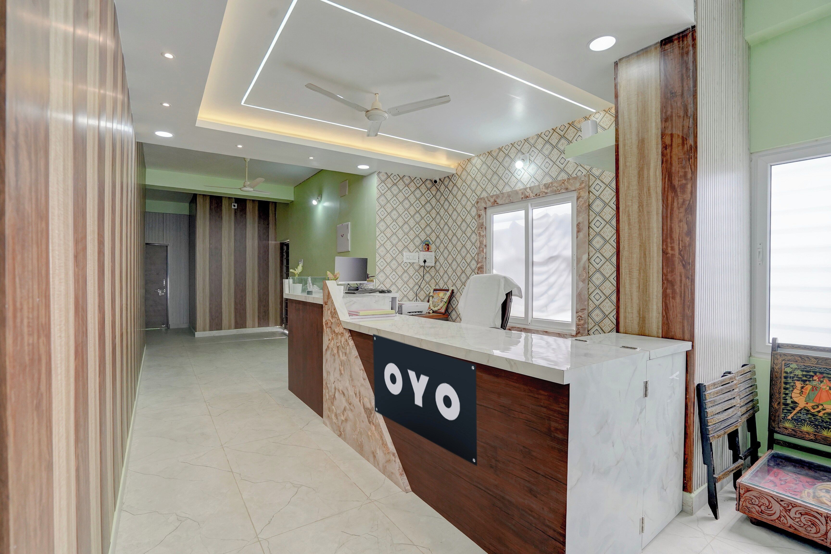 Una recepción con un letrero que dice 'OYO', un ventilador de techo y una pared con diseño.