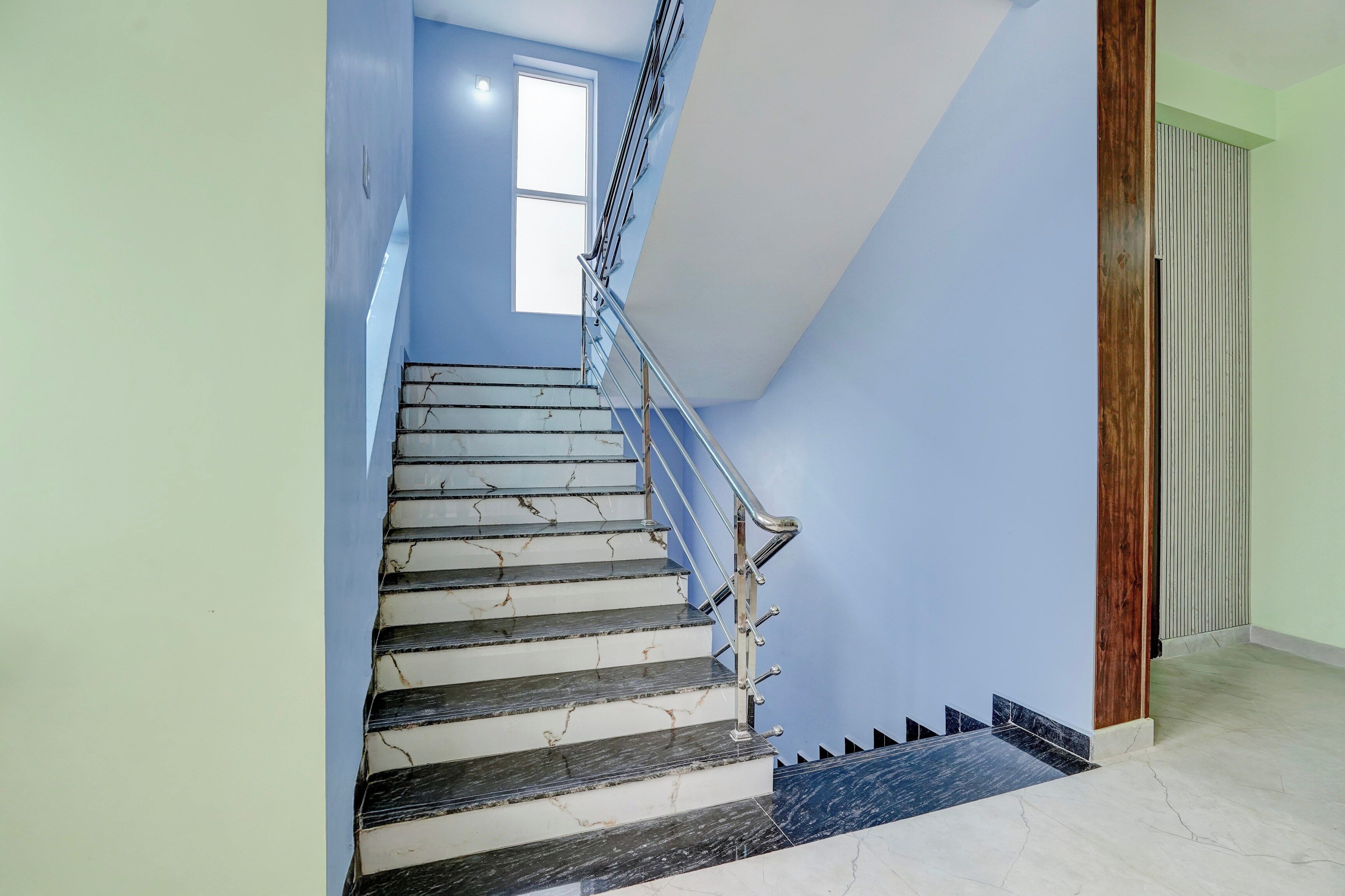Una escalera con barandilla y un ventanal en la parte superior.
