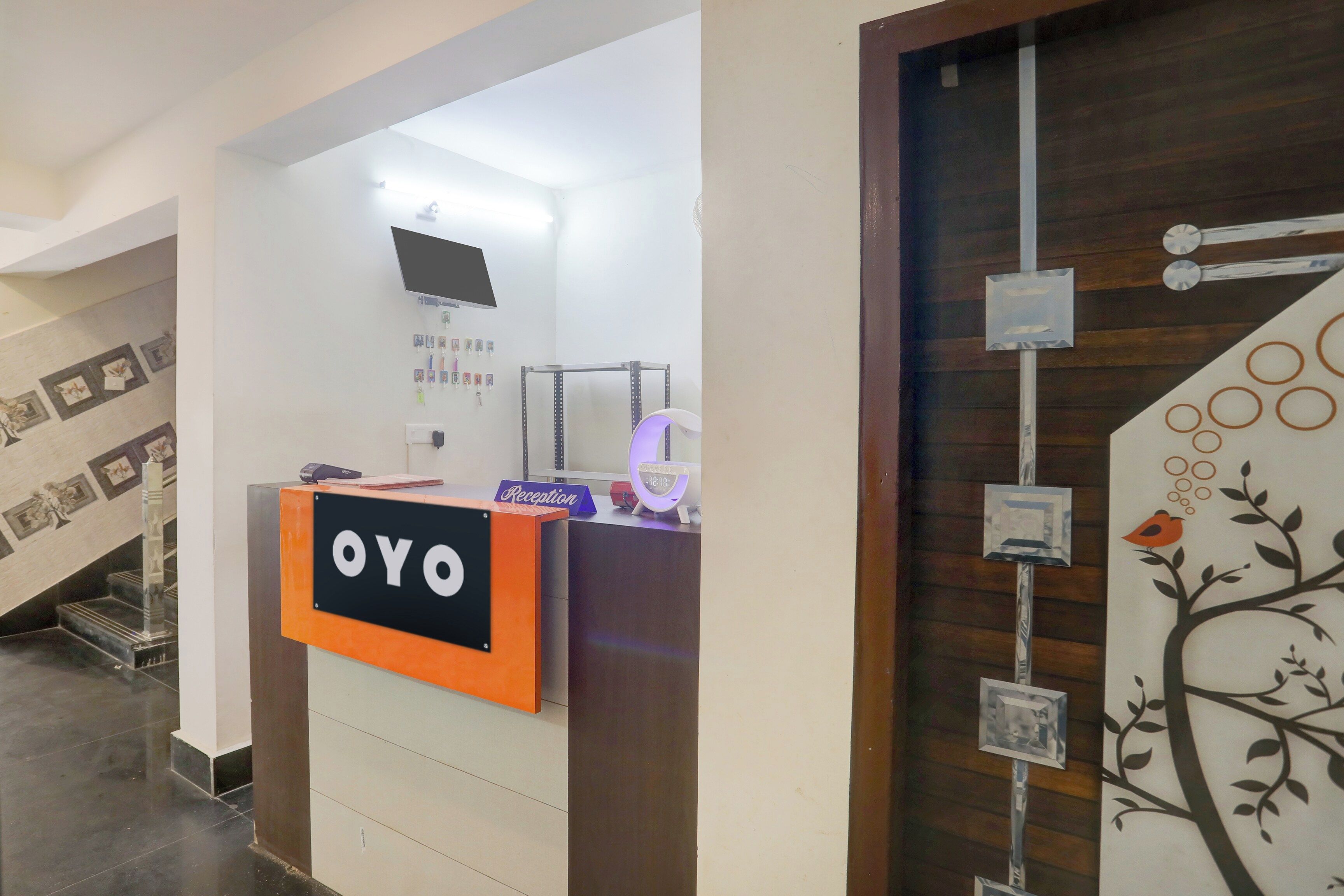 Un mostrador de recepción con un letrero que dice 'OYO' y un reloj marcando las 12:11.