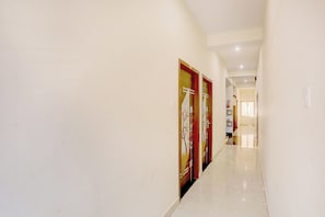 Un pasillo con piso pulido que conduce a una habitación con cama y ventana.