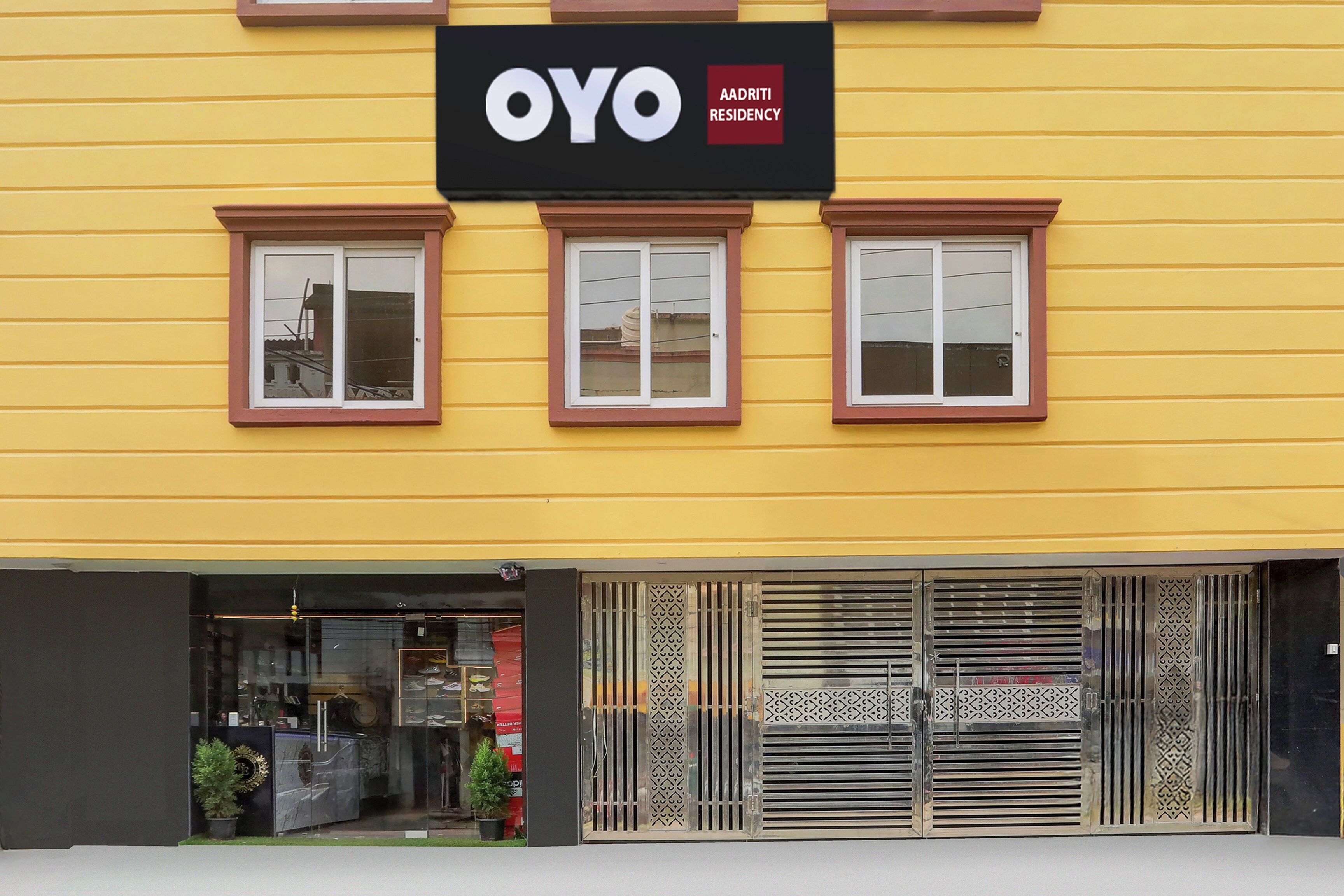 Un edificio amarillo con un letrero que dice 'OYO AADRITI RESIDENCY'.