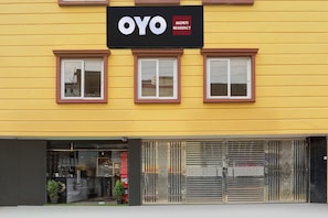 Un edificio amarillo con un letrero que dice 'OYO AADRITI RESIDENCY'.