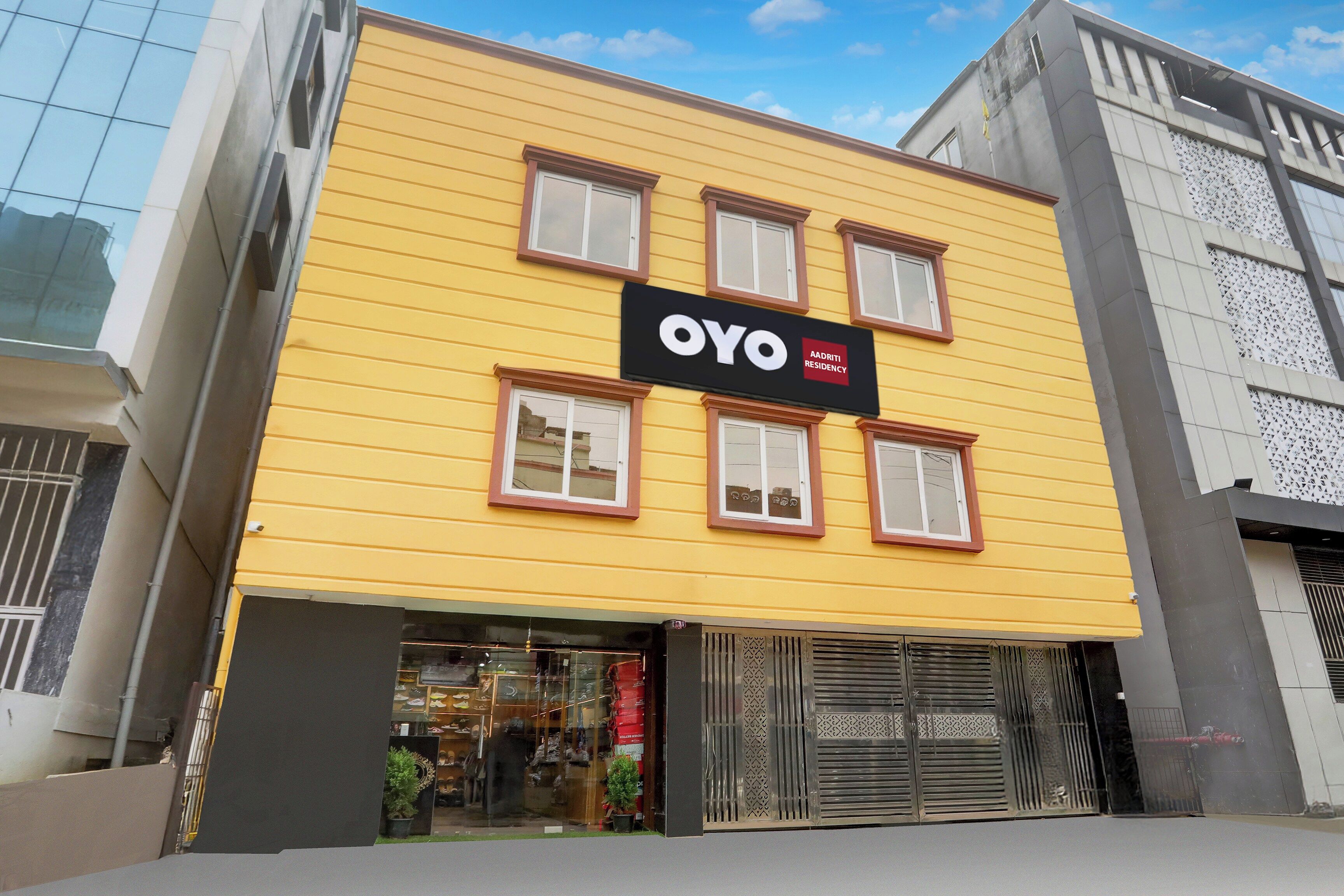 Un edificio amarillo con un letrero negro que dice 'OYO AADRITI RESIDENCY'.