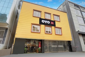 Un edificio amarillo con un letrero negro que dice 'OYO AADRITI RESIDENCY'.
