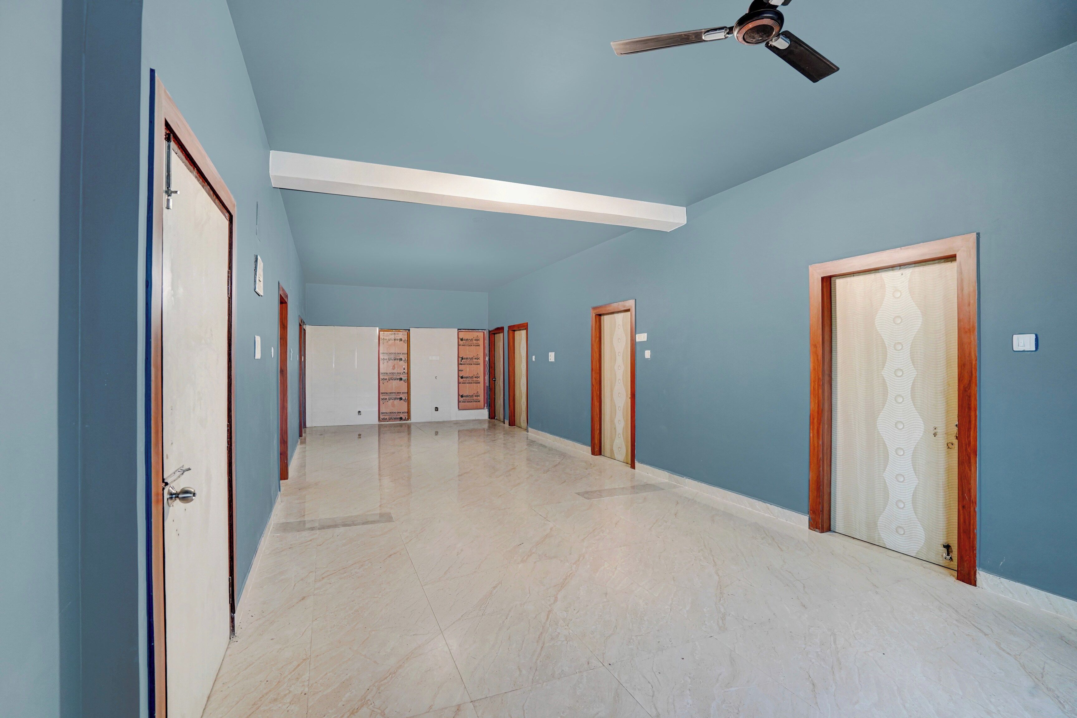 Un pasillo con ventilador de techo, interruptores de luz y puertas que dan a varias habitaciones.