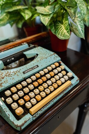 Une machine à écrire Imperial 2000 vintage, posée sur une surface en bois, avec une plante en pot en arrière-plan.