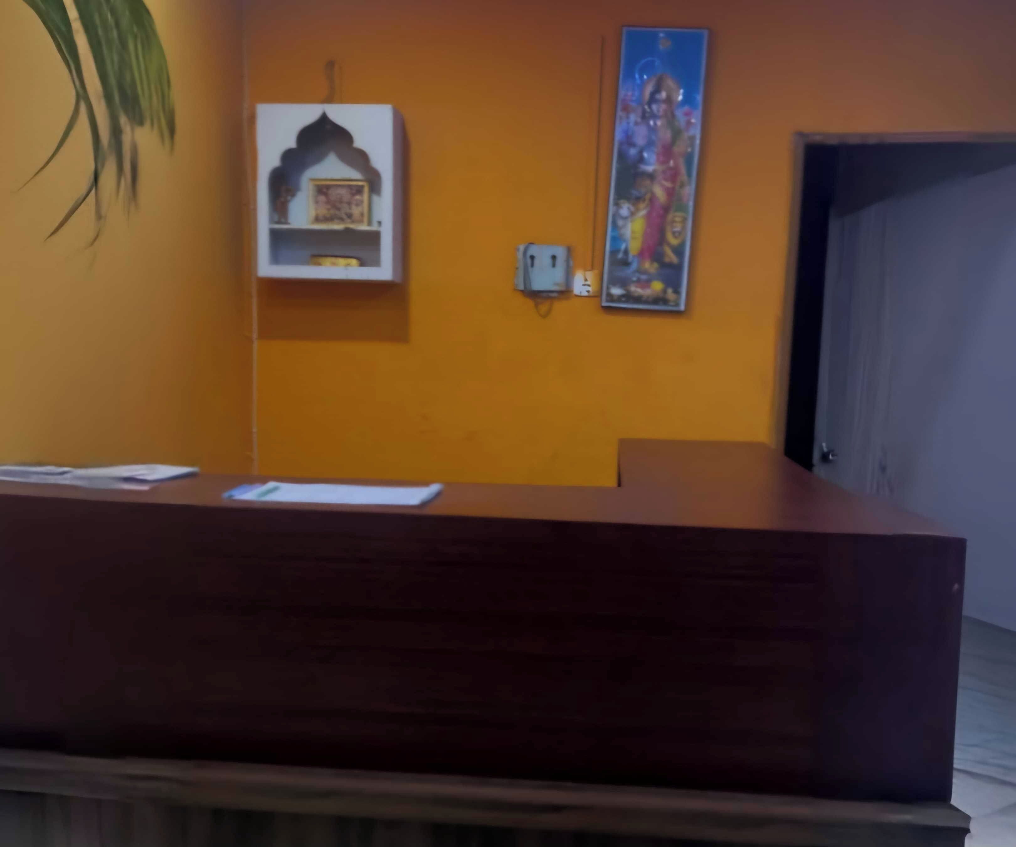 Un mostrador de recepción con acabado de madera oscura, un pequeño estante con un cuadro enmarco y un enchufe instalado en la pared.