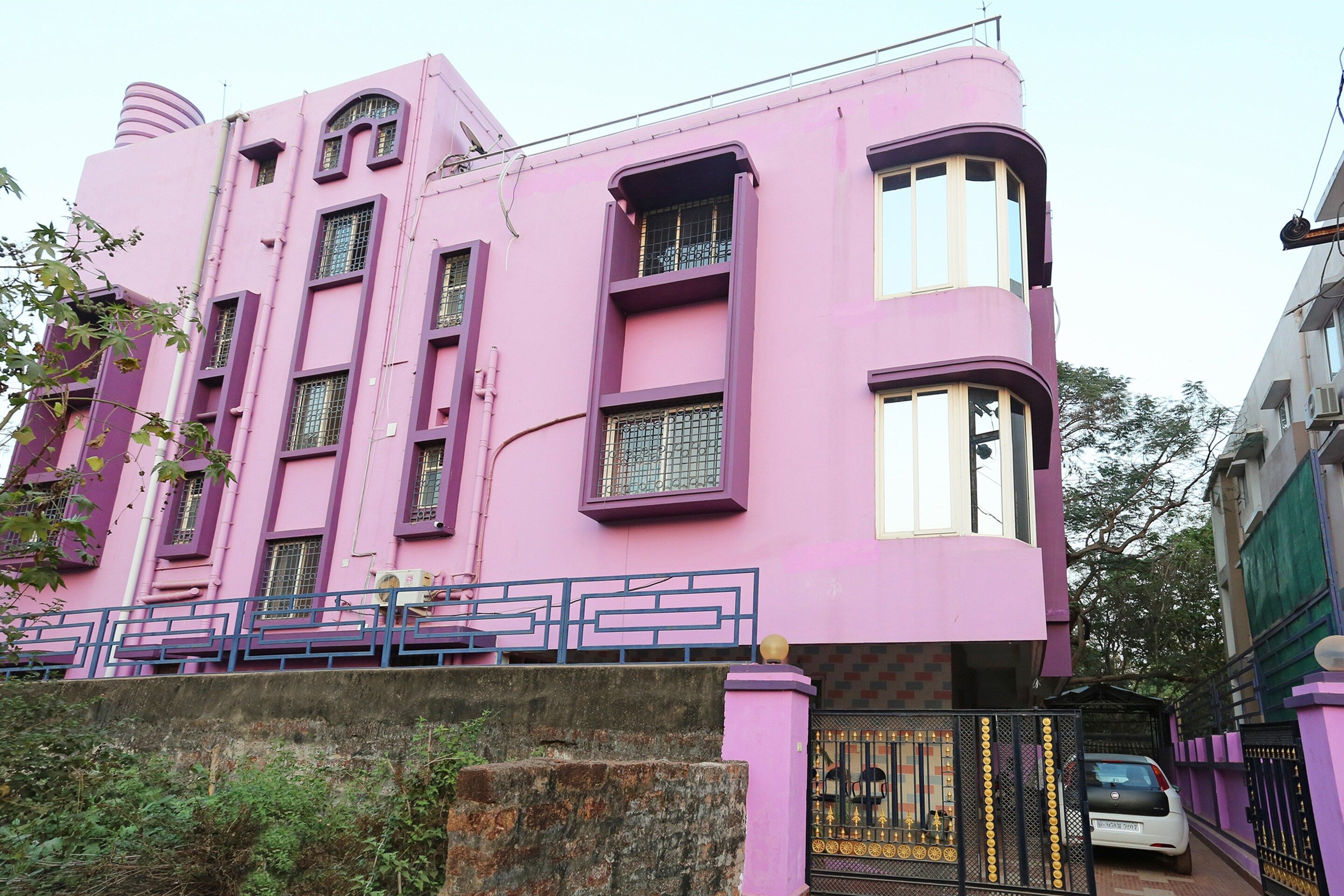 A pink building with multiple windows and a gated entrance.