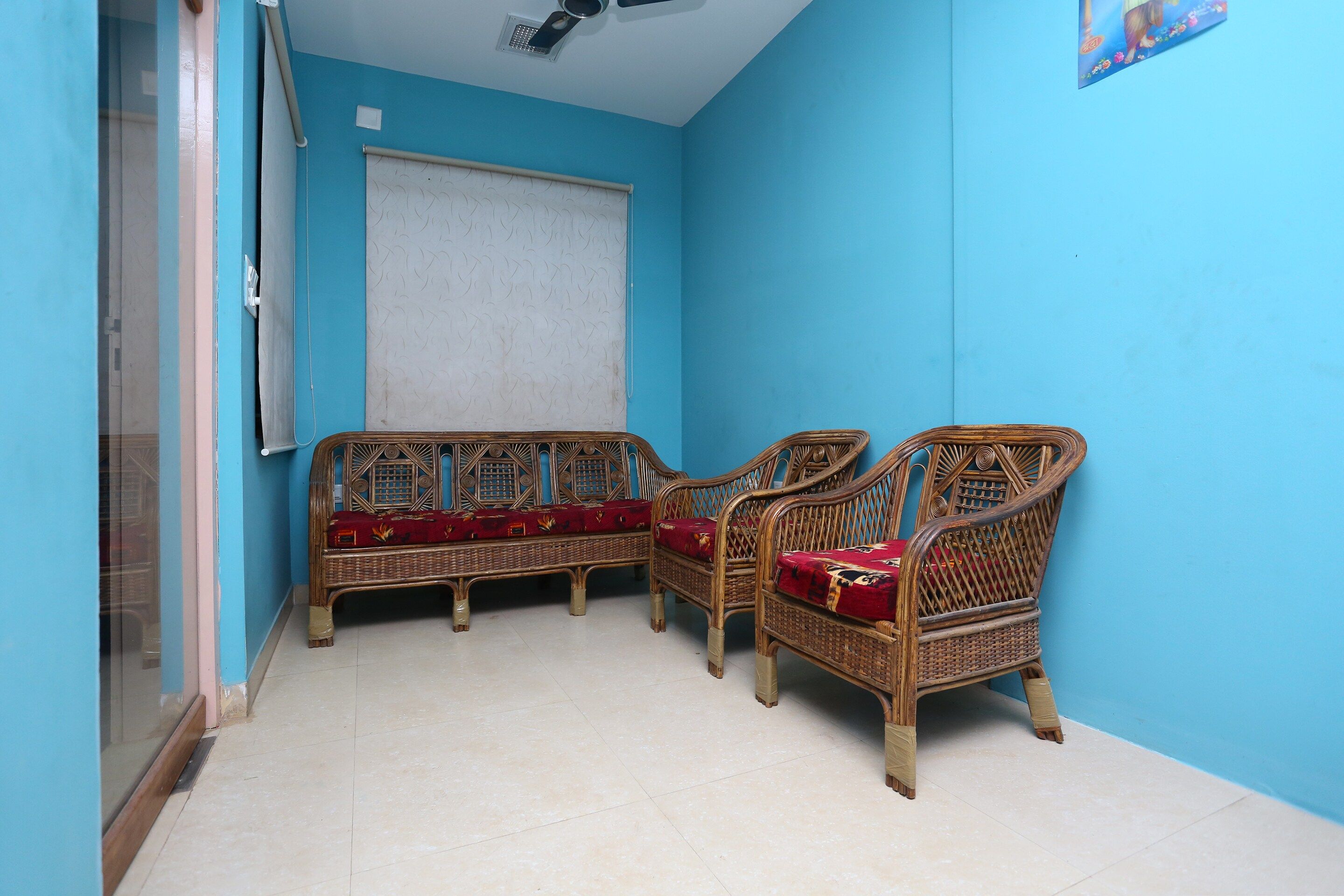 A room with two wicker sofas with red cushions, a white curtain, and a tiled floor.