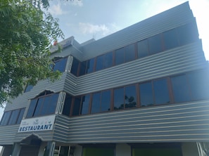 Ein modernes Gebäude mit einem Restaurantschild, großen Fenstern und einem Hauseingang in der Ecke.