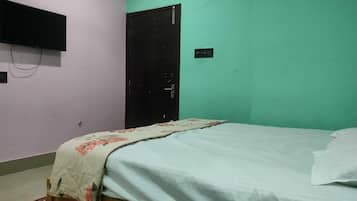 Una habitación con una cama, un televisor en la pared y una puerta.