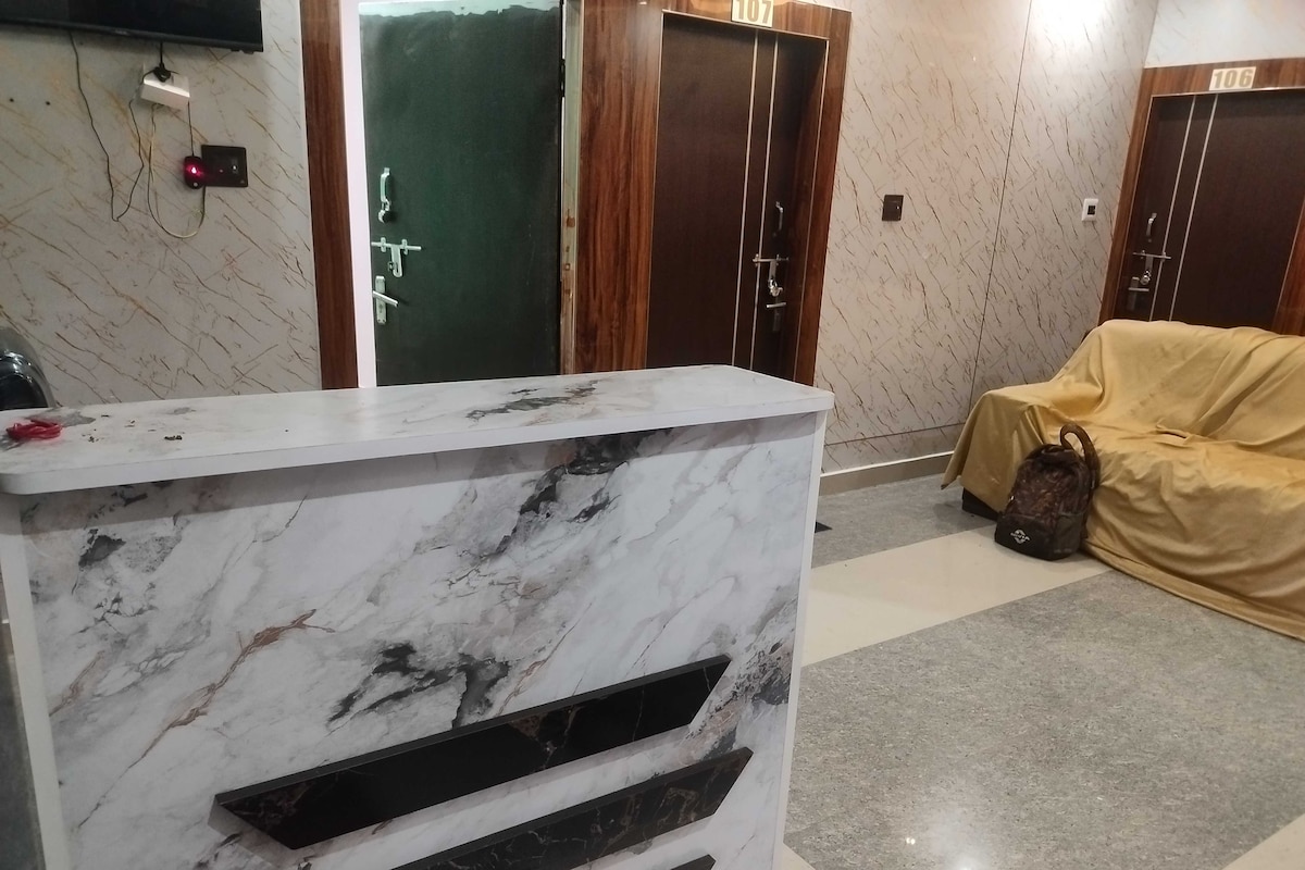 A reception desk with a marble finish, a coat rack with a bag, and a door with a number sign.