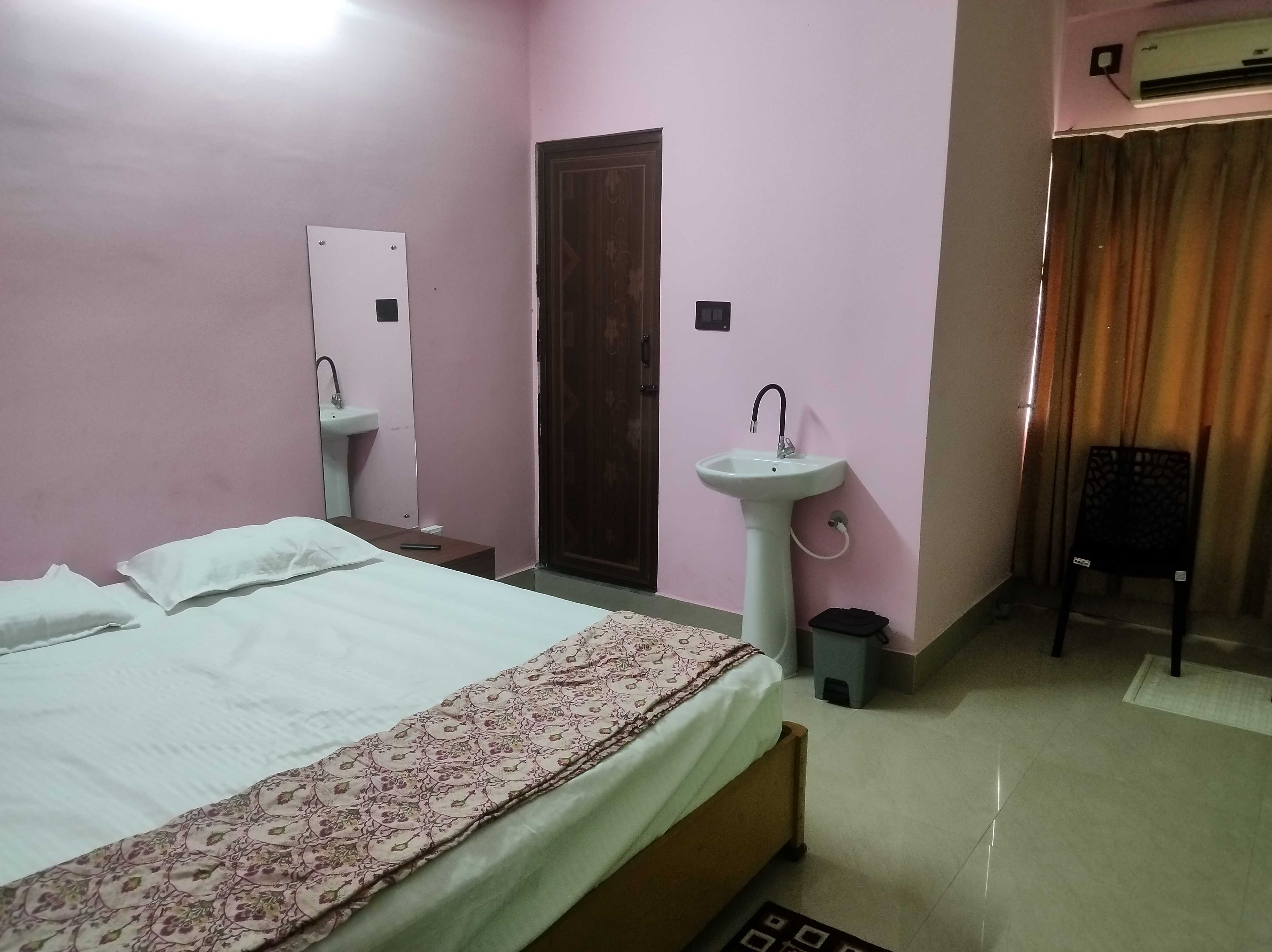 Un dormitorio con cama, dos lavamanos, una puerta y un equipo de aire acondicionado.