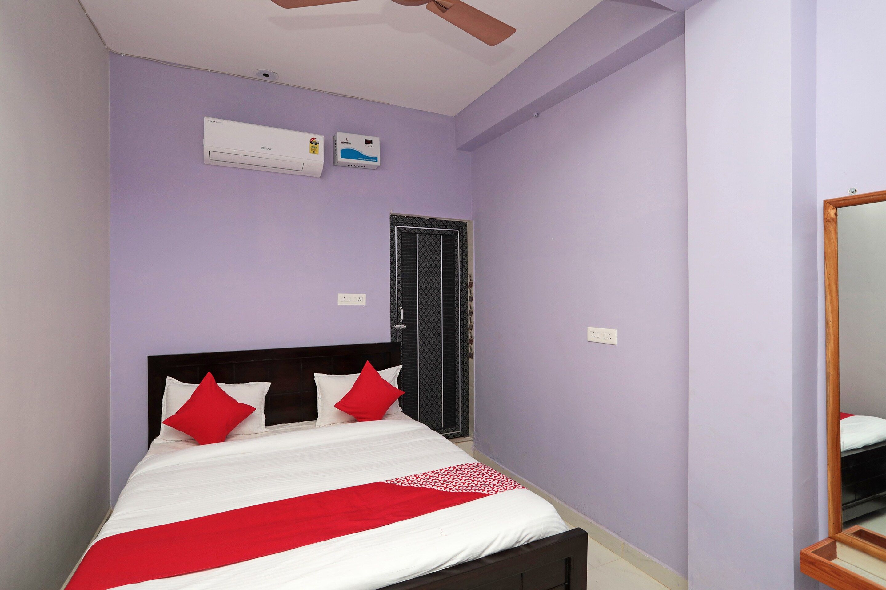 Una habitación con cama, ventilador de techo, aire acondicionado y una puerta.