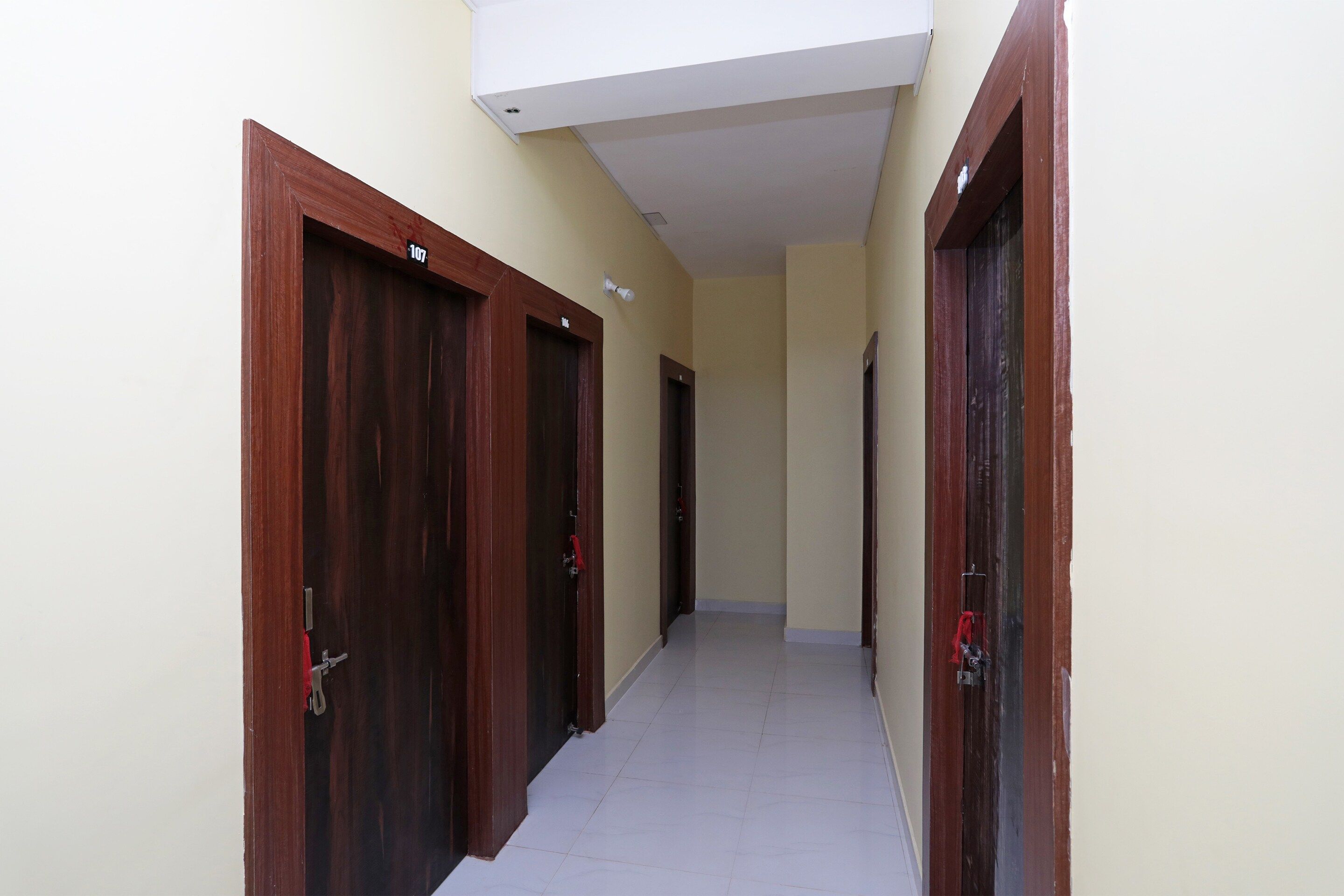 Un pasillo con puertas de madera, numeradas 107, que conduce a habitaciones individuales.
