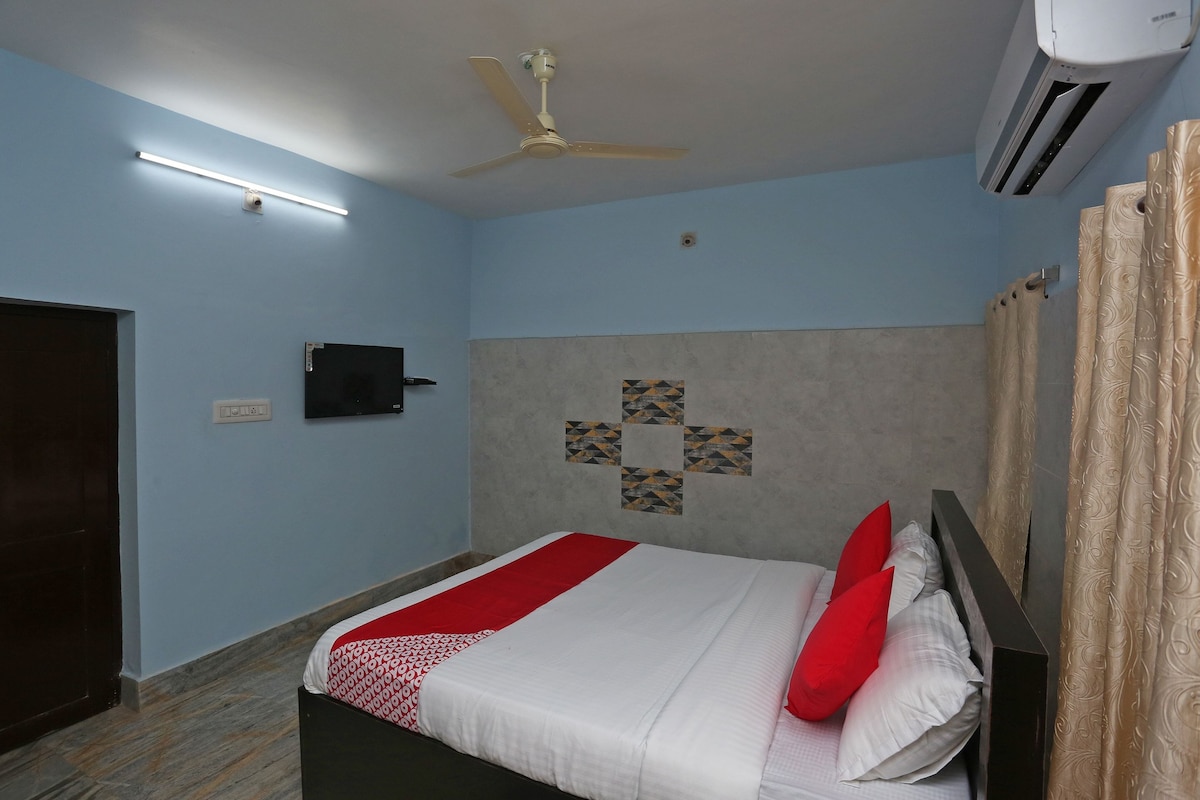 Un dormitorio con cama, ventilador de techo, aire acondicionado, televisor de pantalla plana y decoración mural estampada.