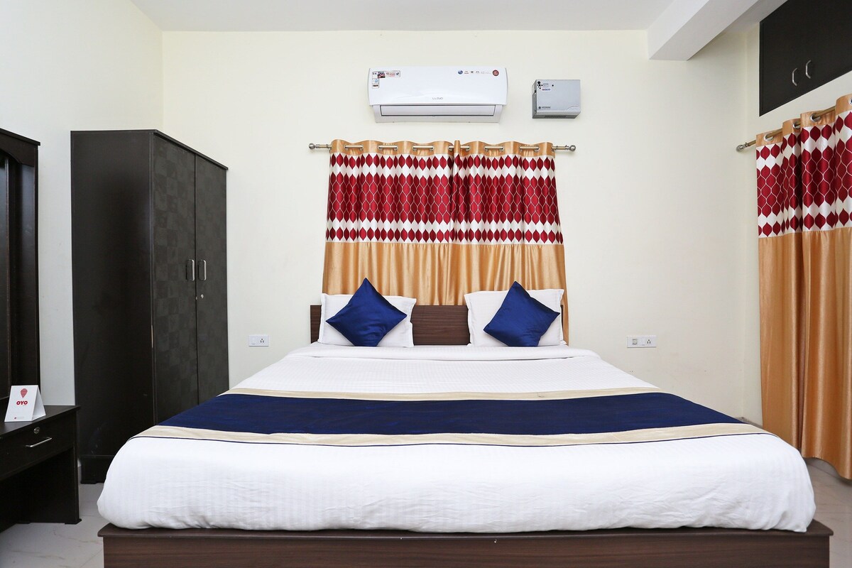 A hotel room with a bed, a wardrobe, an air conditioning unit, and a wall-mounted television.