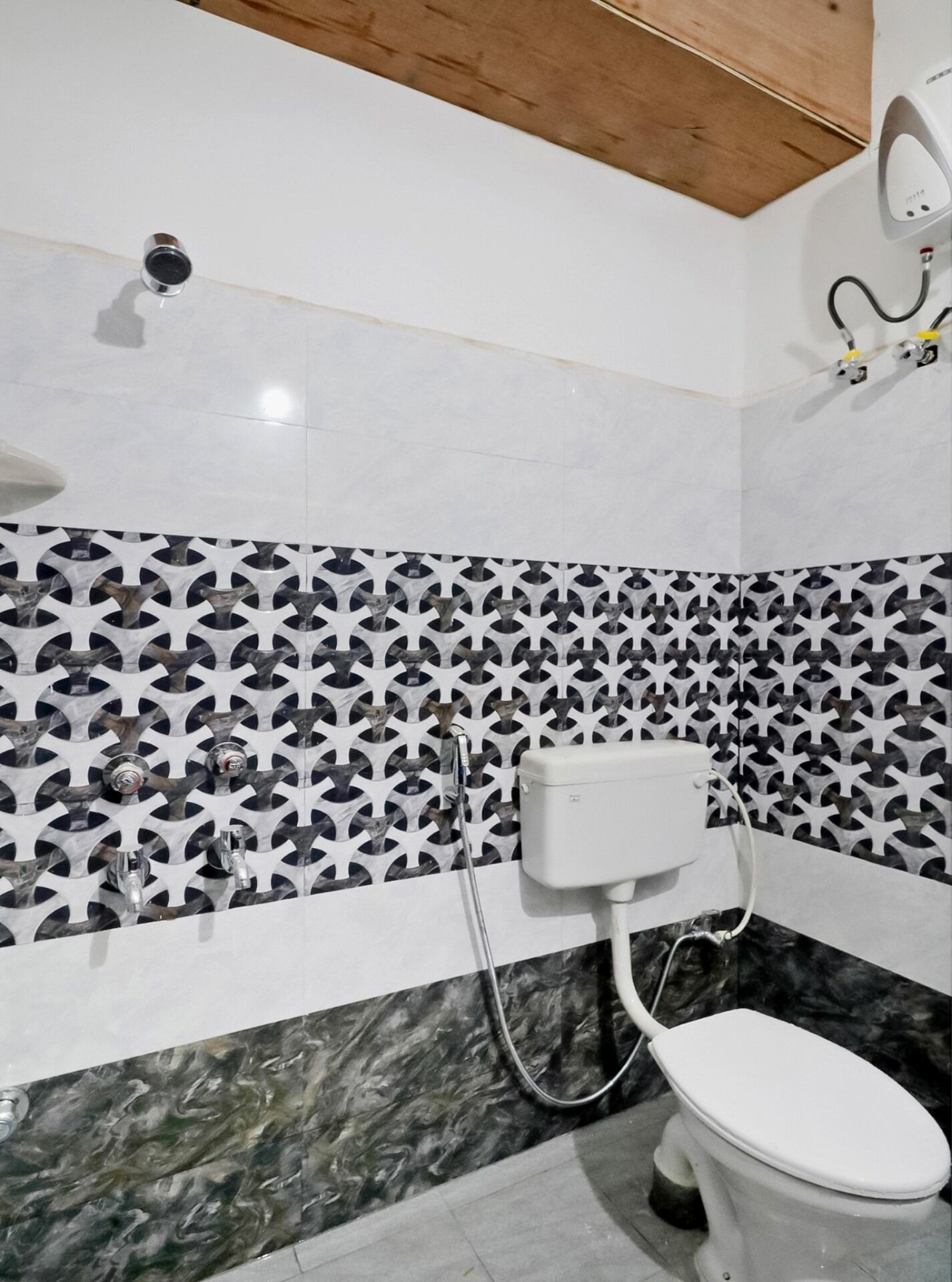 Casa de banho com sanita, chuveiro e parede estampada.