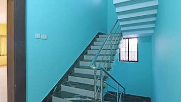 A staircase with a metal railing, a window with decorative bars, and a light switch on the wall.