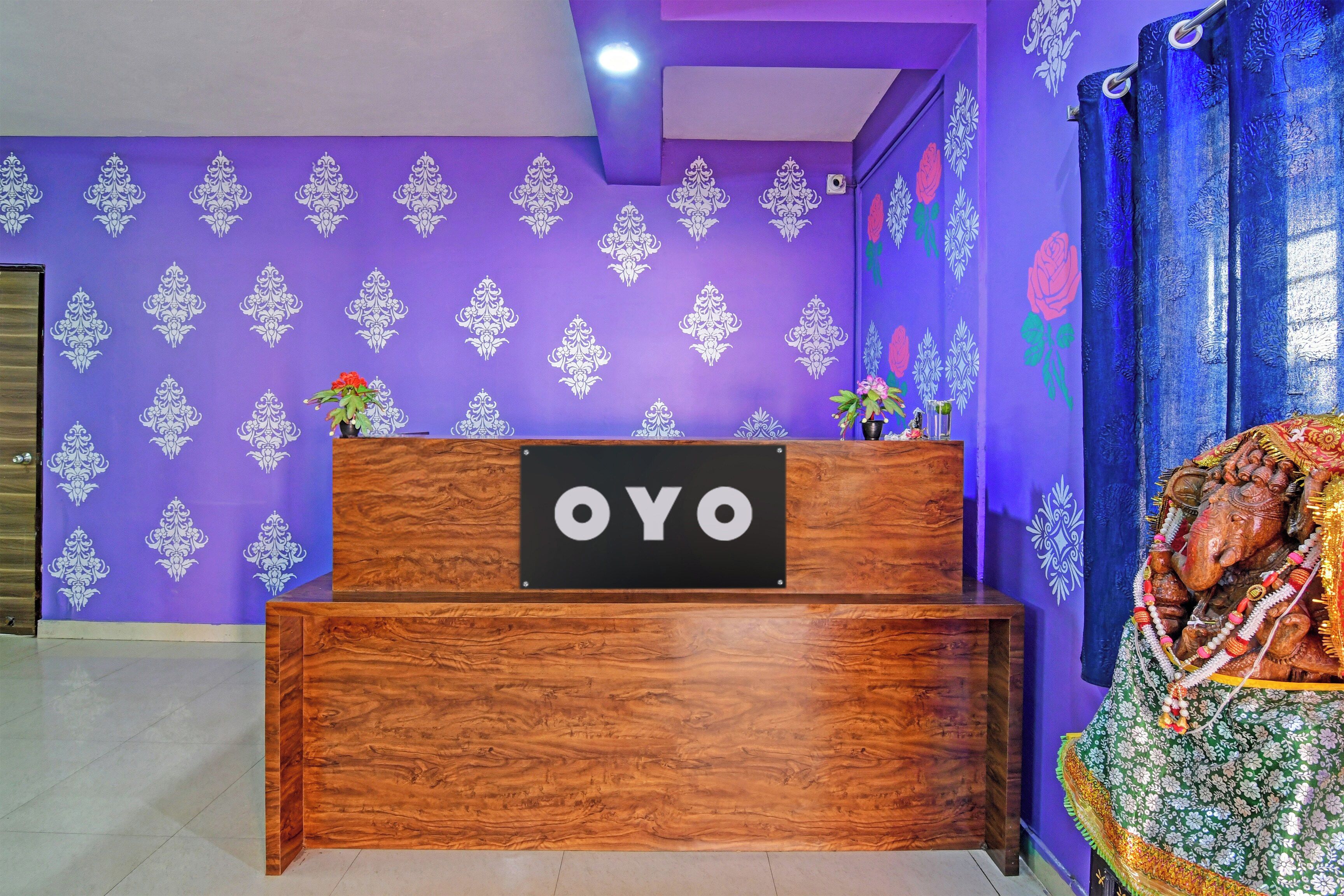 Un mostrador de recepción con un cartel que dice 'OYO' sobre una pared morada con diseños blancos.
